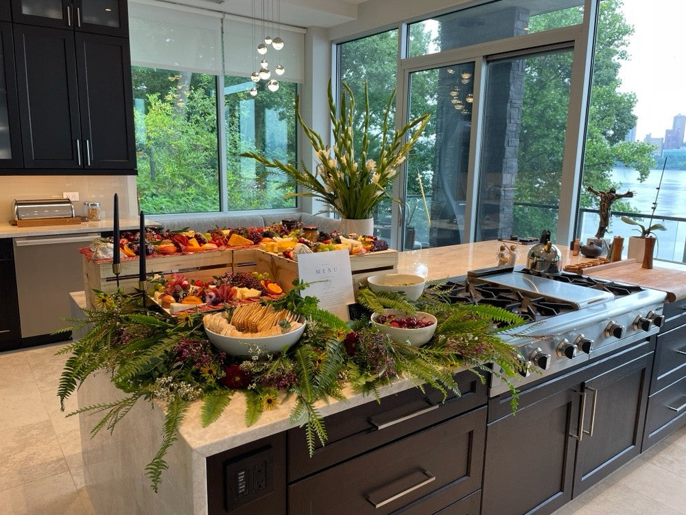 Birch grazing display with seasonal flowers, fresh fruit, and cheese in a light-filled home